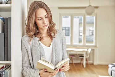 Woman leaning against wall reading book - FMKF03131