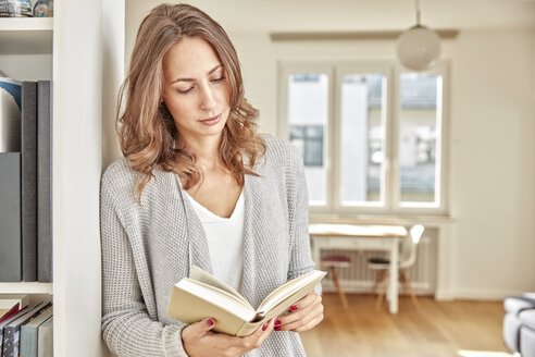 Frau lehnt an der Wand und liest ein Buch - FMKF03131