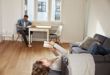 Couple relaxing with book and laptop at home - FMKF03135