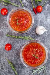 Zwei Gläser mit hausgemachter Tomatensauce und Zutaten auf Stein - SARF03038