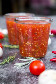 Gläser mit hausgemachter Tomatensauce und Zutaten auf einem Stein - SARF03039