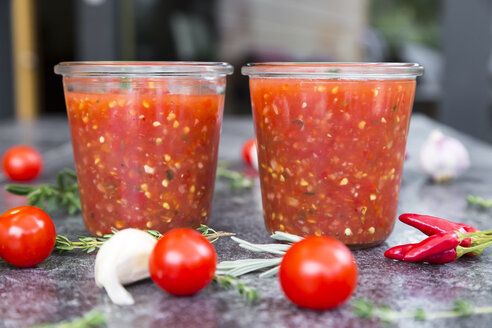 Zwei Gläser mit hausgemachter Tomatensauce und Zutaten auf Stein - SARF03040
