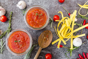 Two glasses of homemade tomato sauce, ingredients and pasta on stone - SARF03042