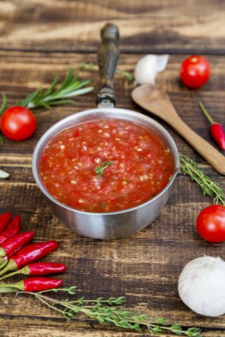 Kochtopf mit hausgemachter Tomatensauce und Zutaten auf Holz, lizenzfreies Stockfoto