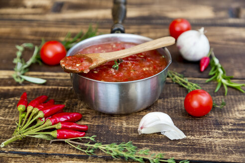 Kochtopf mit hausgemachter Tomatensauce und Zutaten auf Holz - SARF03046