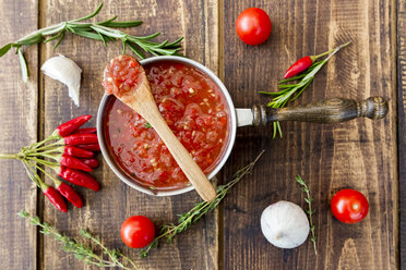 Saucepan of homemade tomato sauce and ingredients on wood - SARF03047