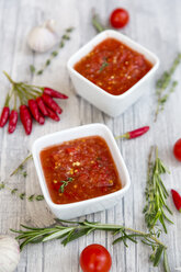 Zwei Schalen mit hausgemachter Tomatensauce und Zutaten auf Holz - SARF03048