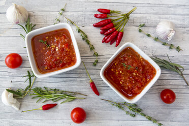 Zwei Schalen mit hausgemachter Tomatensauce und Zutaten auf Holz - SARF03049