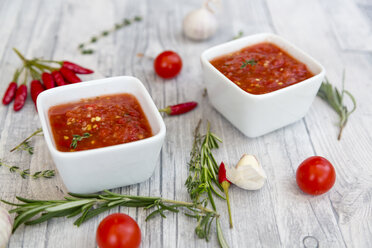 Two bowls of homemade tomato sauce and ingredients on wood - SARF03050