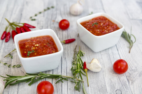 Zwei Schalen mit hausgemachter Tomatensauce und Zutaten auf Holz - SARF03050