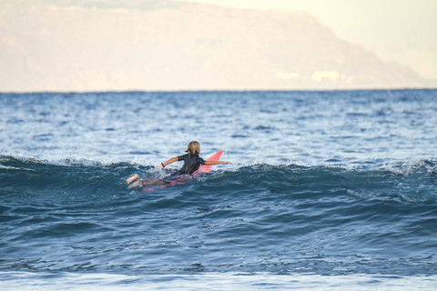 Spanien, Teneriffa, Junge beim Surfen im Meer, lizenzfreies Stockfoto