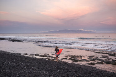 Spanien, Teneriffa, Junge mit Surfbrett am Strand bei Sonnenuntergang - SIPF01005