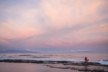 Spanien, Teneriffa, Junge mit Surfbrett am Strand bei Sonnenuntergang - SIPF01007