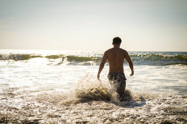 Mexico, Nuevo Vallarta, Riviera Nayarit, young man entering the ocean - ABAF02093