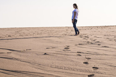 Junge Frau, die im Sand am Strand spazieren geht - SIPF01010