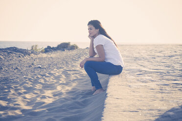 Junge Frau sitzt am Strand - SIPF01014