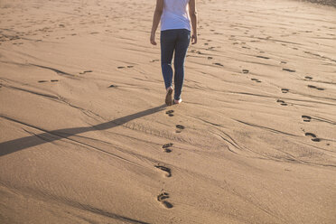 Junge Frau, die im Sand am Strand spazieren geht - SIPF01015