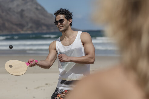 Young couple playing beach paddles on the beach - ZEF11291