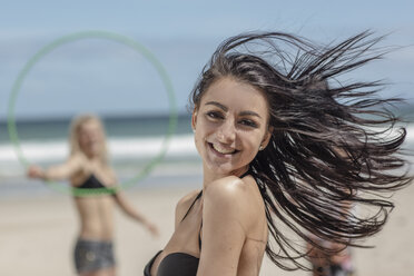 Glückliche junge Frau am Strand mit Freunden im Hintergrund - ZEF11293