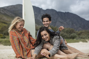 Happy friends with surfboard sitting together on the beach - ZEF11314