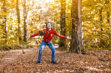 Laughing boy throwing leaves in the air in the autumnal forest - DIGF01399