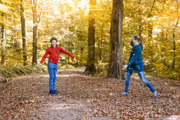 Mother and son throwing with autumn leaves in the forest - DIGF01402