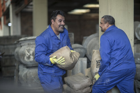 Zwei Männer tragen Säcke in einer industriellen Töpferei - ZEF11355