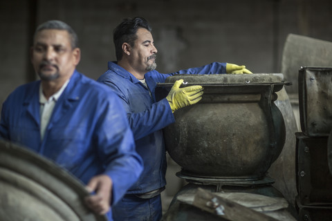 Zwei Männer arbeiten in einer Fabrik für Industrietöpfe, lizenzfreies Stockfoto