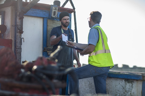 Fischer auf Trawler im Gespräch mit Inspektor, lizenzfreies Stockfoto