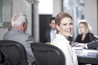 Erfolgreiche Geschäftsfrau sitzt in einer Konferenz und schaut in die Kamera - ZEF11446