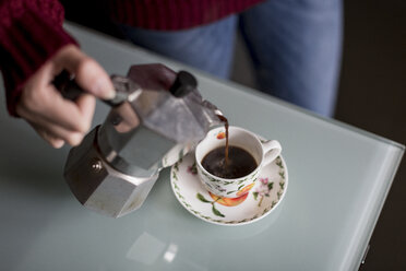 Hand einer jungen Frau, die Kaffee in eine Tasse gießt - MAUF00851
