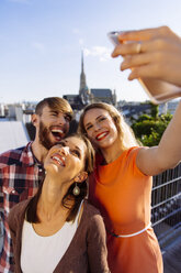 Österreich, Wien, drei Freunde machen ein Selfie auf einer Dachterrasse mit dem Stephansdom im Hintergrund - AIF00412