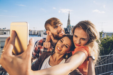 Österreich, Wien, drei Freunde machen ein Selfie auf einer Dachterrasse mit dem Stephansdom im Hintergrund - AIF00413