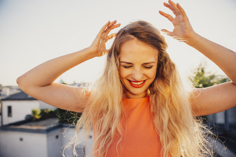 Smiling blond woman dancing on rooftop terrace stock photo