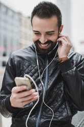 Smiling man with smartphone and earphones - MAUF00890