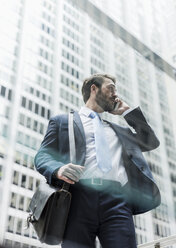 USA, New York City, businessman in Manhattan on cell phone - UUF08930