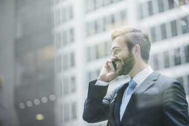 USA, New York City, lächelnder Geschäftsmann in Manhattan am Mobiltelefon - UUF08936