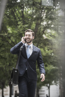 Lächelnder Geschäftsmann am Mobiltelefon - UUF08937