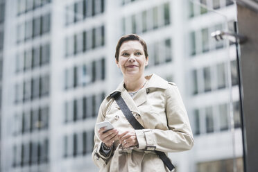 USA, New York City, lächelnde Frau in Manhattan mit Mobiltelefon - UUF08940