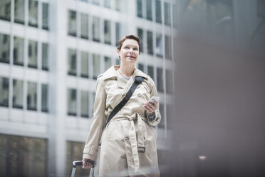 USA, New York City, lächelnde Frau in Manhattan mit Mobiltelefon - UUF08943