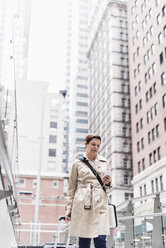 USA, New York City, businesswoman on the go with cell phone and earphones - UUF08953