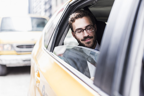 USA, New York City, lächelnder Geschäftsmann in einem Taxi, lizenzfreies Stockfoto