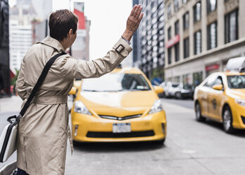 USA, New York City, Frau in Manhattan, die ein Taxi ruft - UUF08978