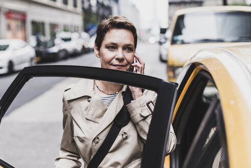 USA, New York City, Frau in Manhattan telefoniert beim Einsteigen in ein Taxi - UUF08982