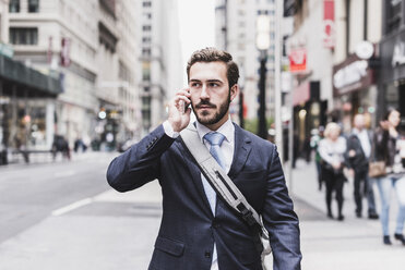 USA, New York City, businessman in Manhattan on cell phone - UUF08993