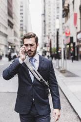 USA, New York City, businessman in Manhattan on cell phone - UUF08994