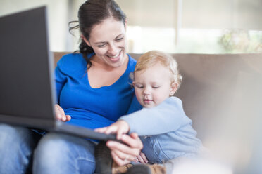 Mother with baby girl using laptop at home - ZEF11503