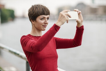 Porträt einer jungen Frau, die ein Selfie mit ihrem Smartphone macht - TAMF00763