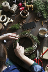 Woman decorating Advent wreath on work table, partial view - RTBF00477