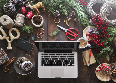 Laptop auf dem Schreibtisch mit Arbeitsmaterial für Adventskränze - RTBF00479